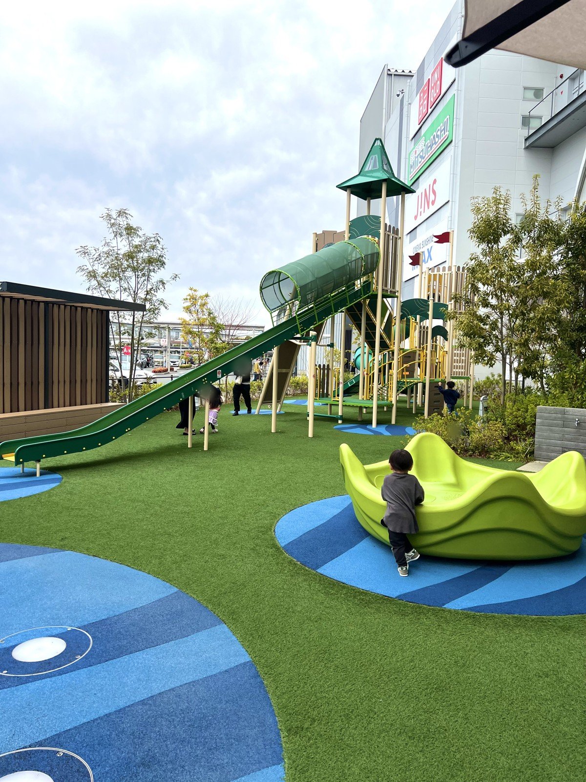 人工芝の広場に、大型遊具と回る遊具が並ぶ