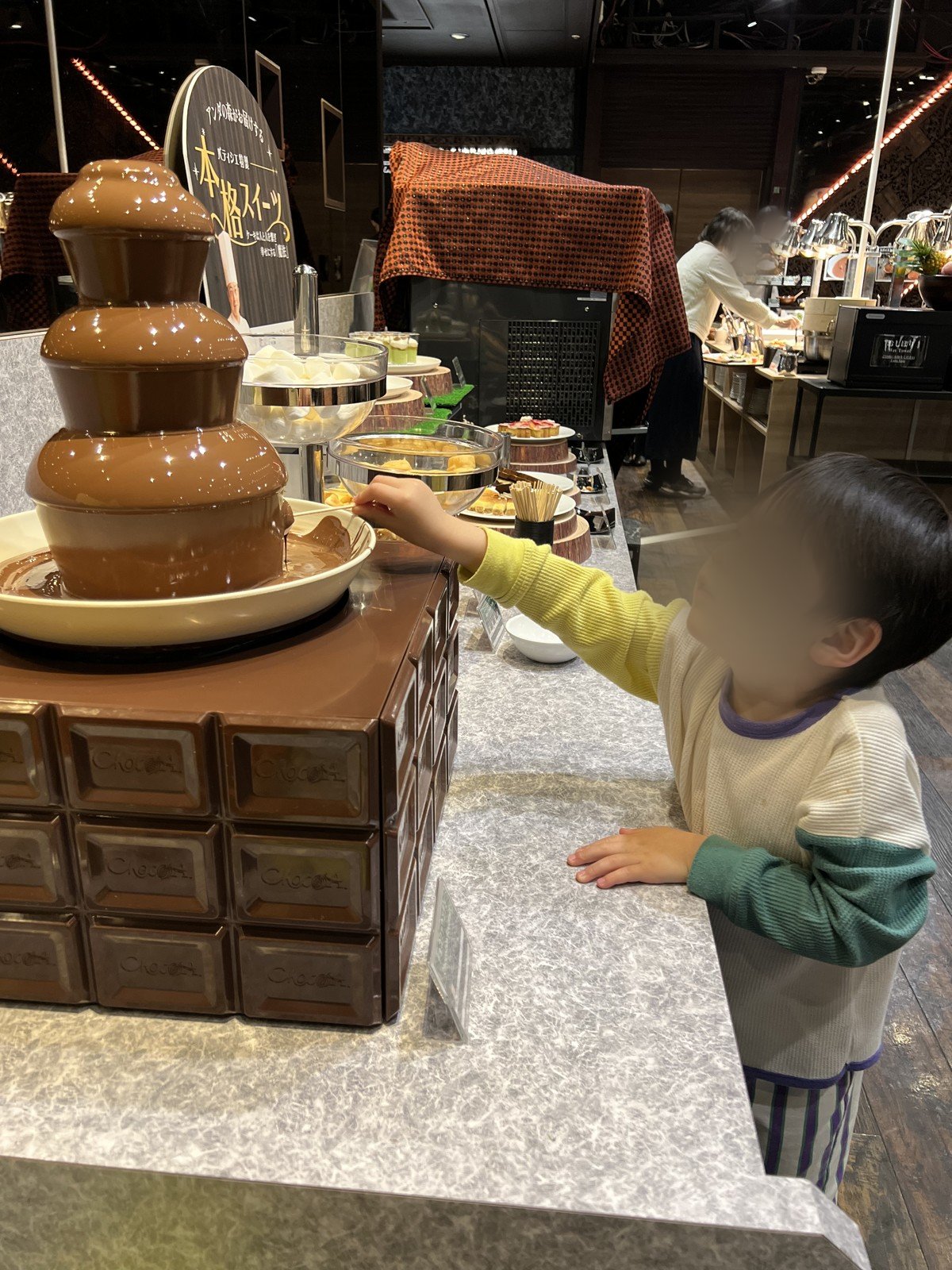 チョコレートファウンテンでマシュマロにチョコをつける息子