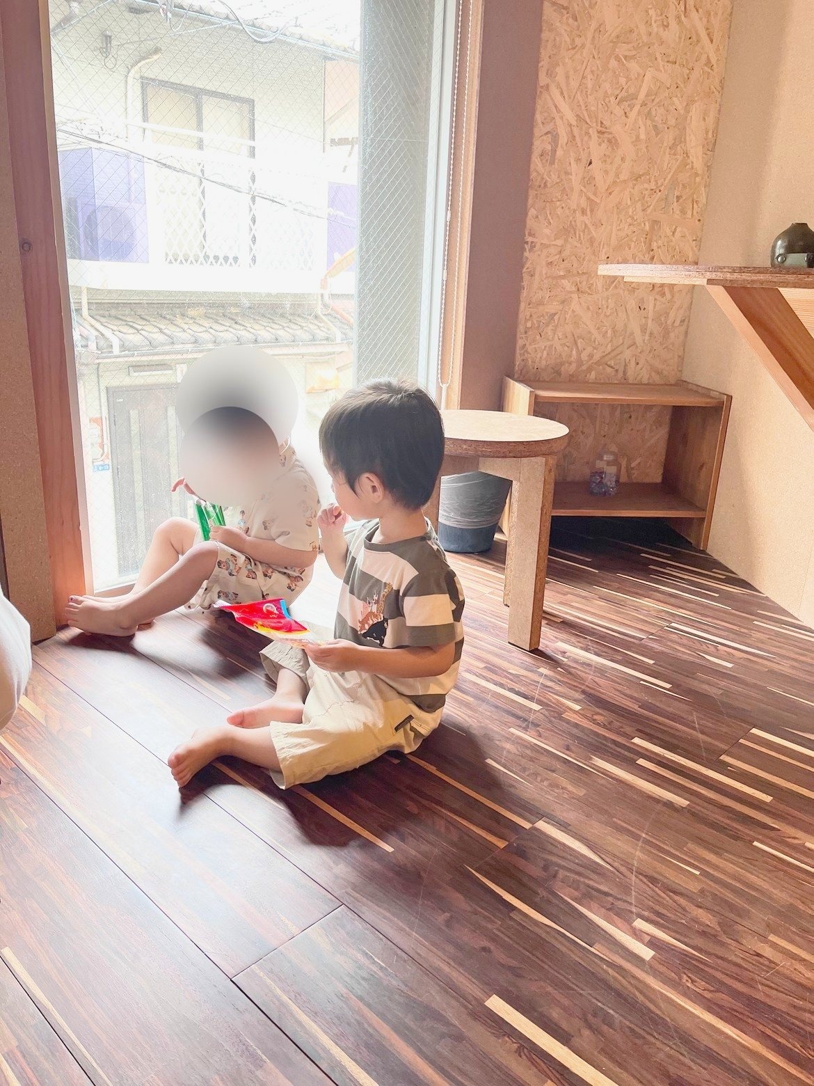 吹き抜けの室内。窓辺の小上がりでおやつを食べる子ども