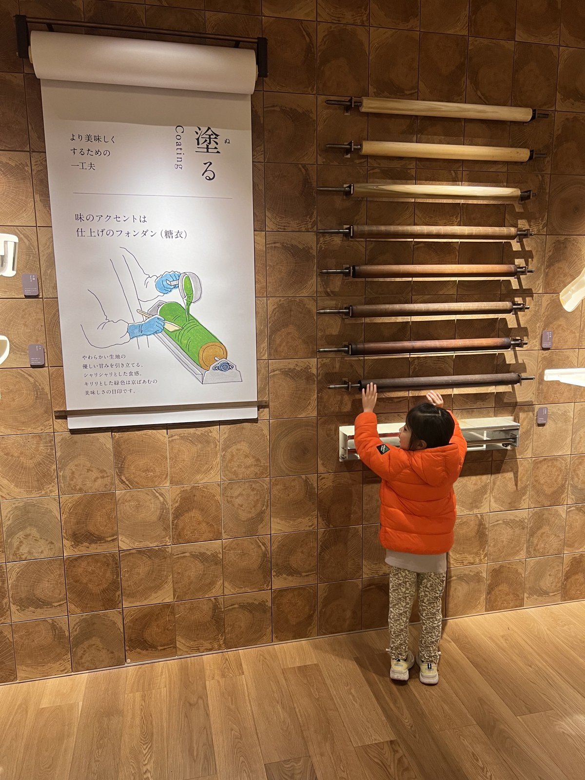 「塗る」の工程を説明する壁の展示。棒がずらりと並んでいる
