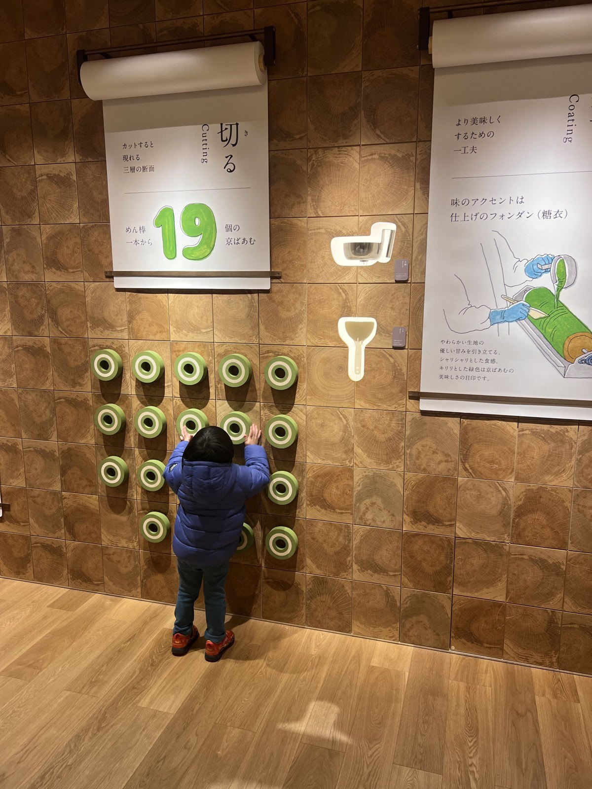 「切る」の工程を説明する壁の展示。緑の丸いパーツが並んでいる