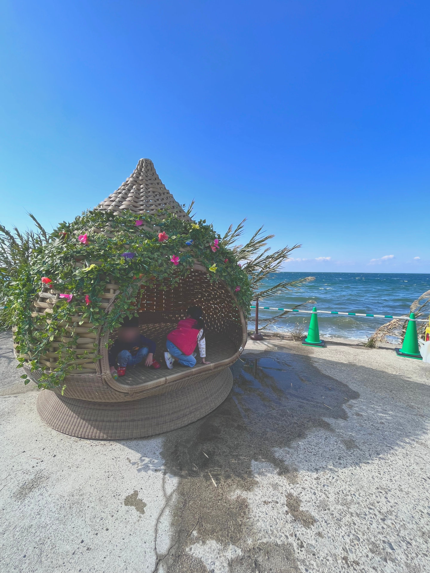 海沿いのかご型の写真スポットに座る子どもたち