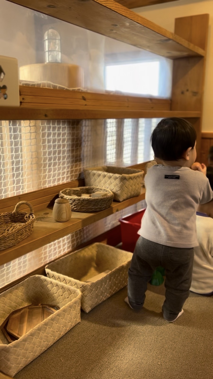 かごが並ぶ棚で遊ぶ子ども