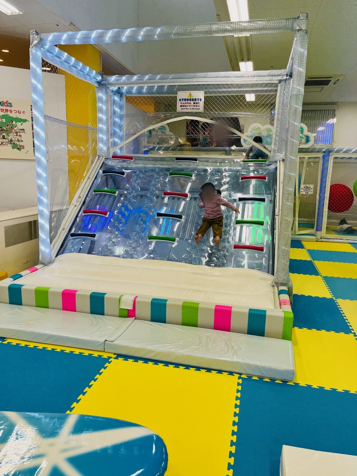 透明のエアー遊具を駆け下りる子ども