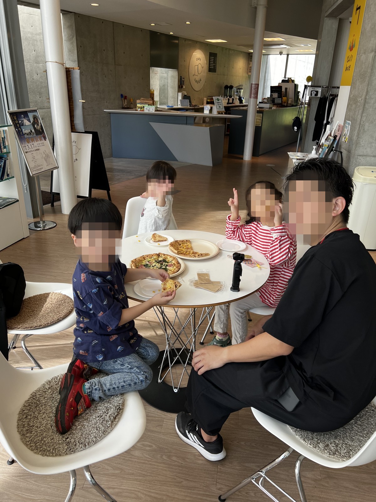 カフェのテーブルでピザを食べる家族