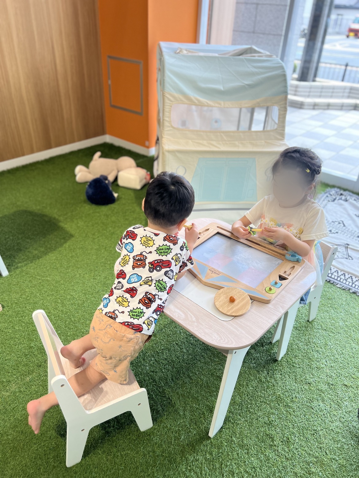 人工芝のキッズスペースでお絵かきをする子どもたち
