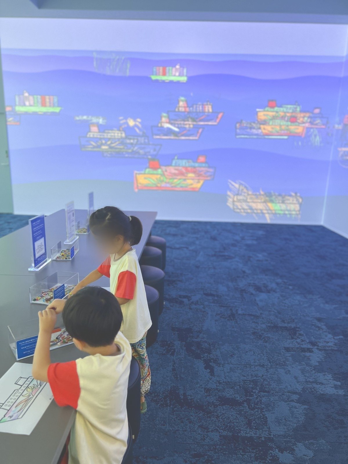 大きなスクリーンの前で操作する子ども