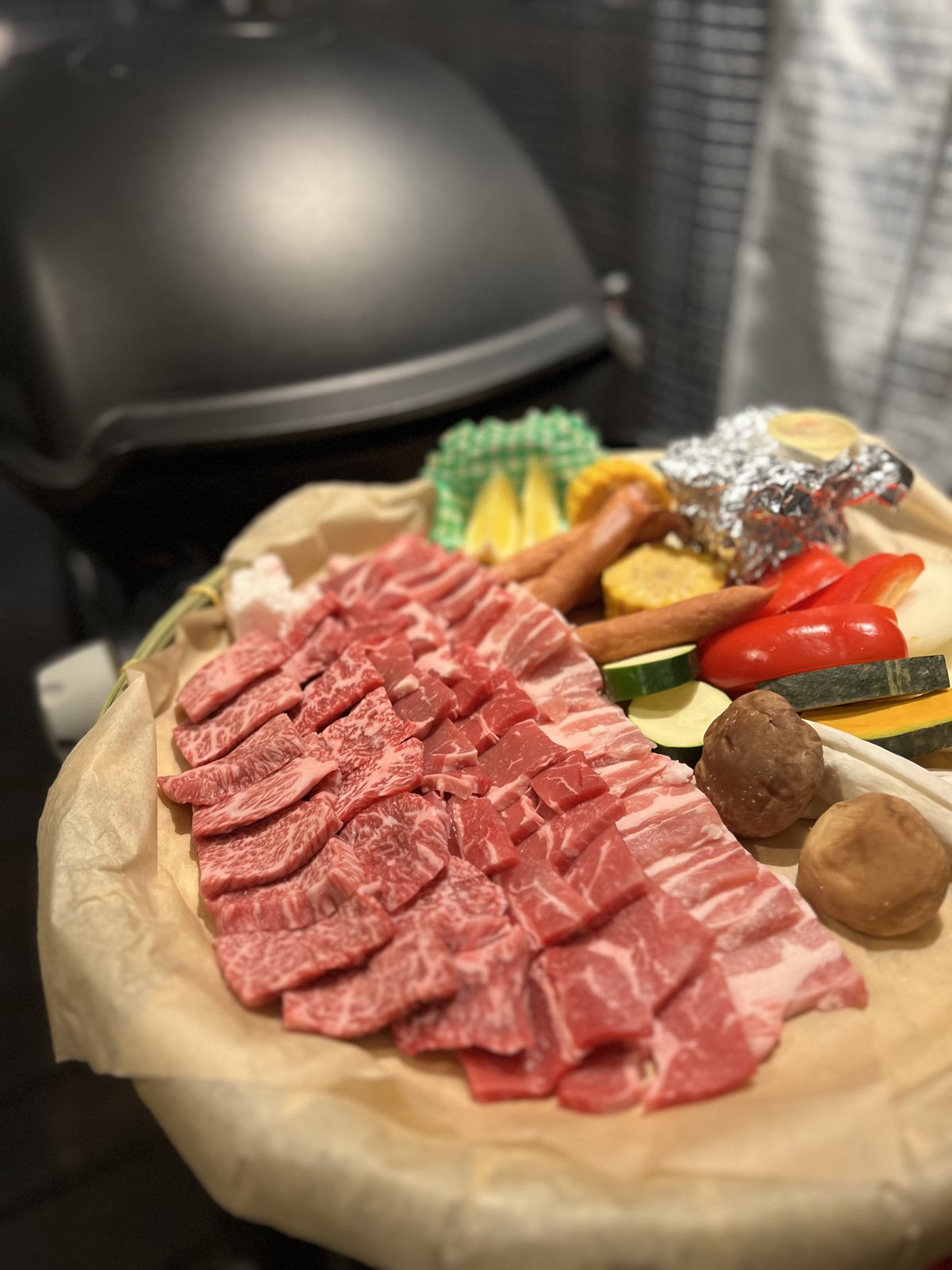 霜降りの牛肉や豚バラ、ソーセージ、野菜が盛られたBBQの食材