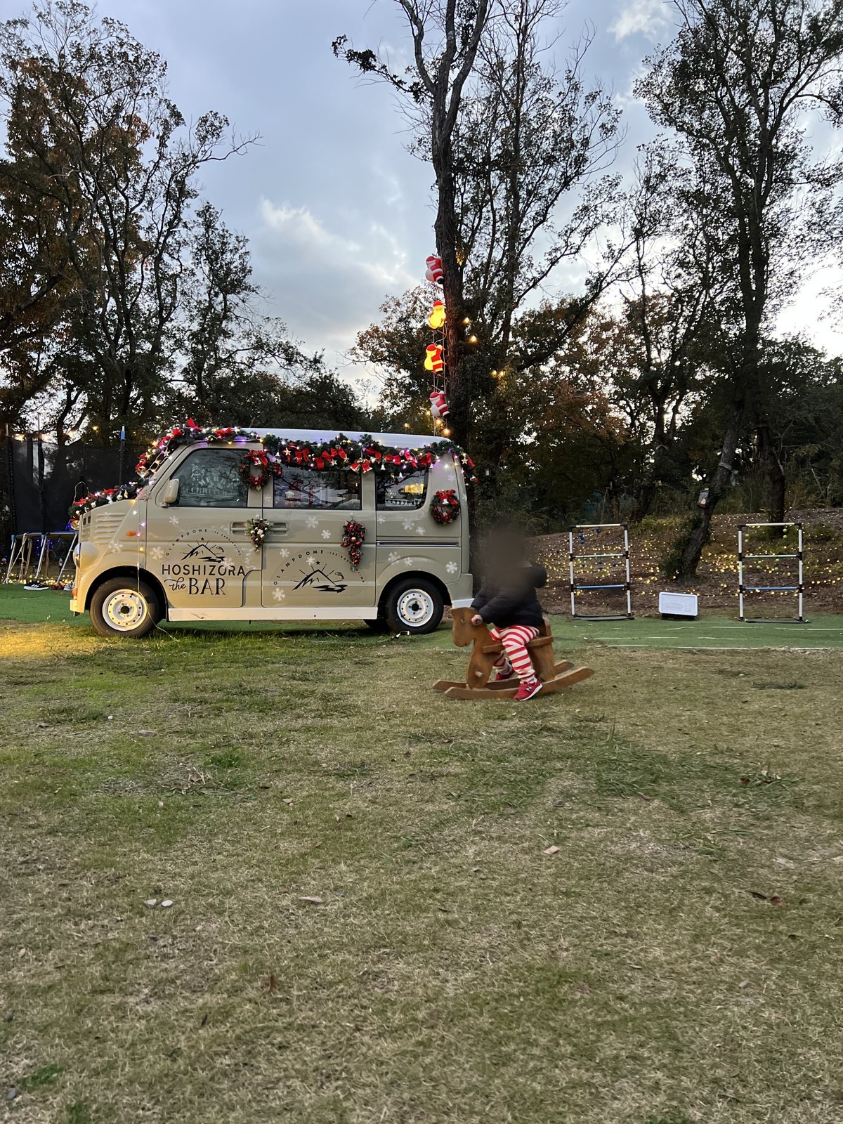 木の揺り木馬で遊ぶ次男と、「HOSHIZORA the BAR」と書かれた車