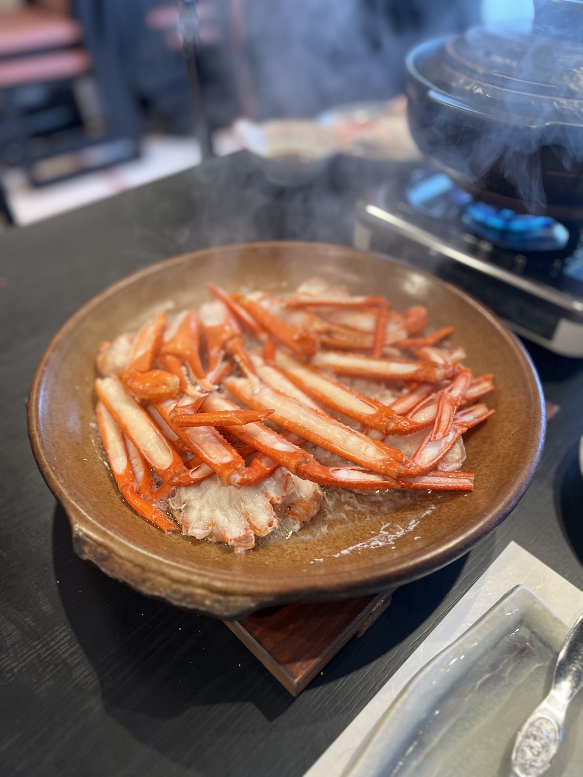 土鍋で焼かれて湯気の立つカニの脚