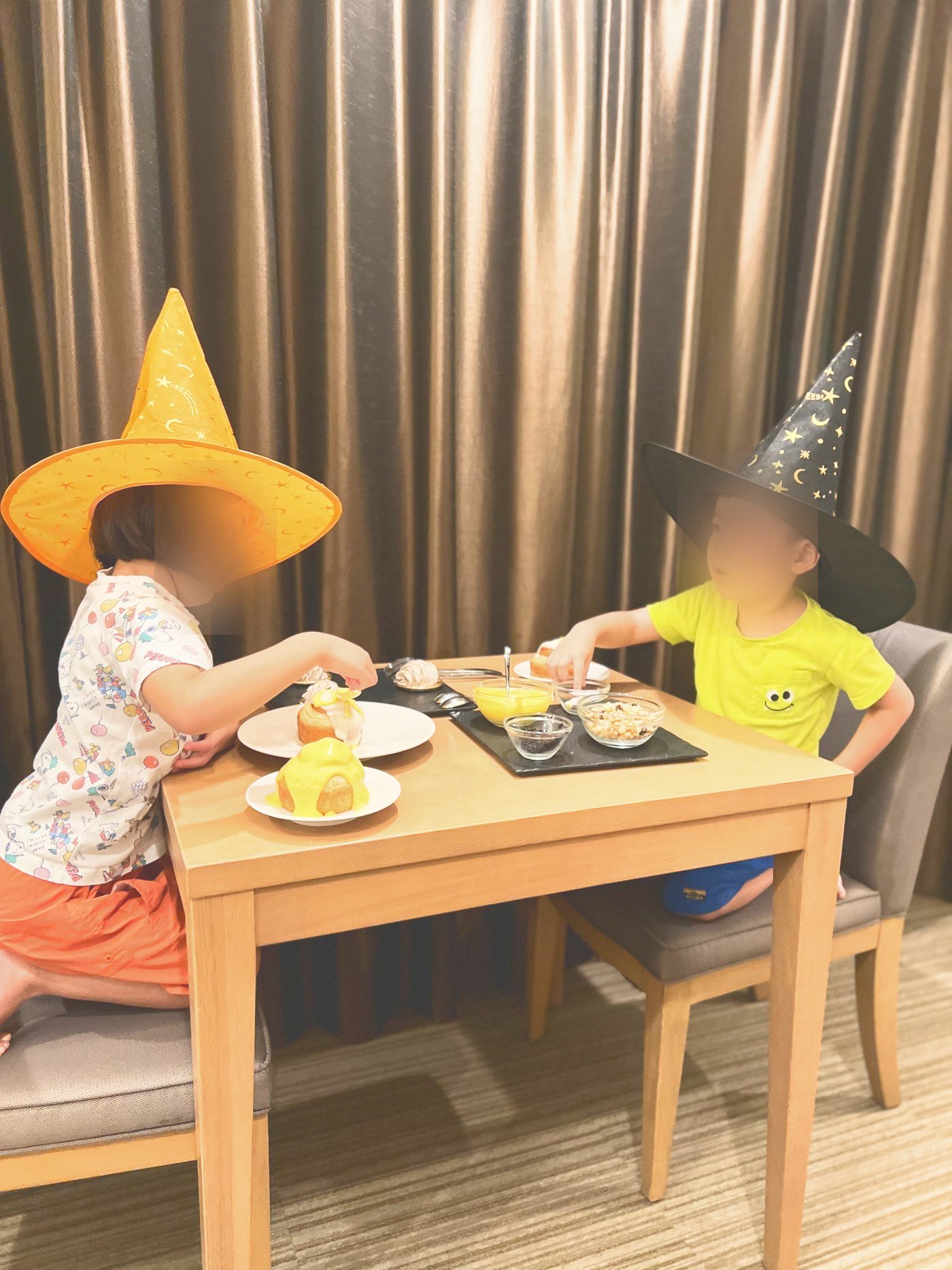 ハロウィンの帽子をかぶってスイーツをデコレーションする子どもたち