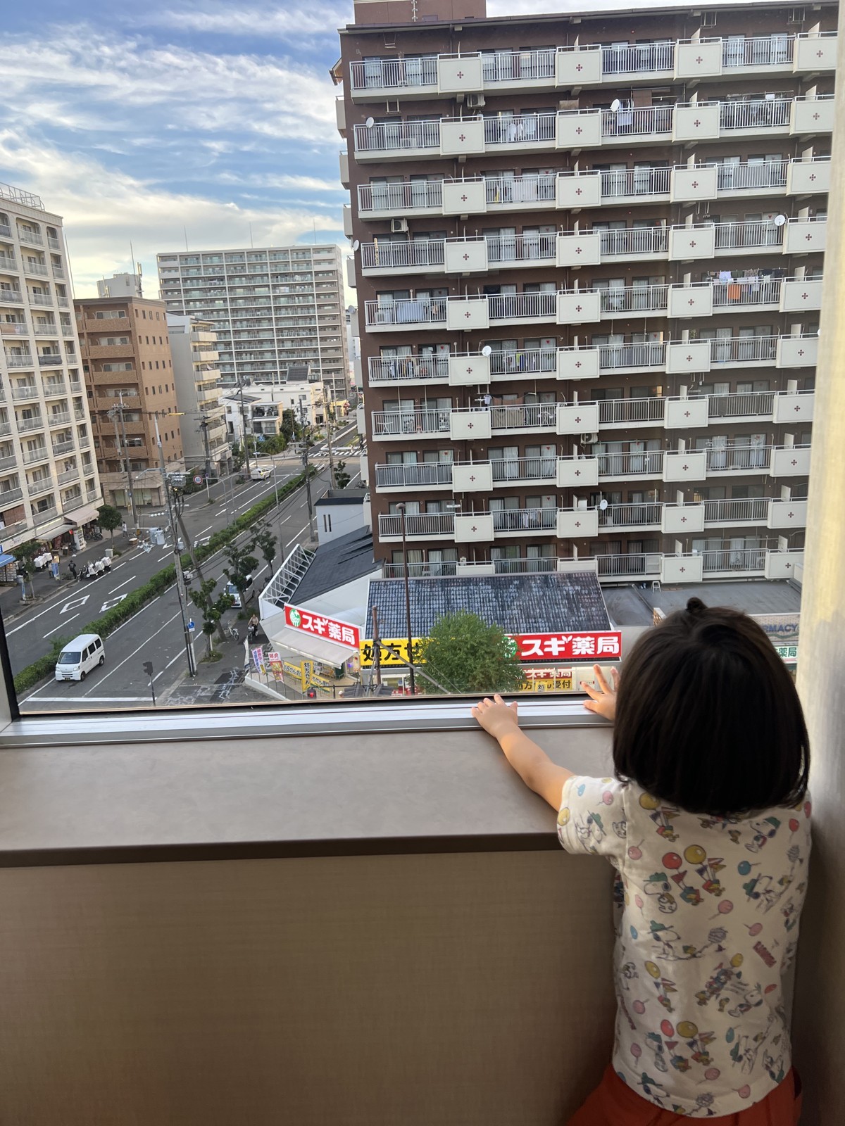 窓の外の新大阪の街並みを眺める子ども