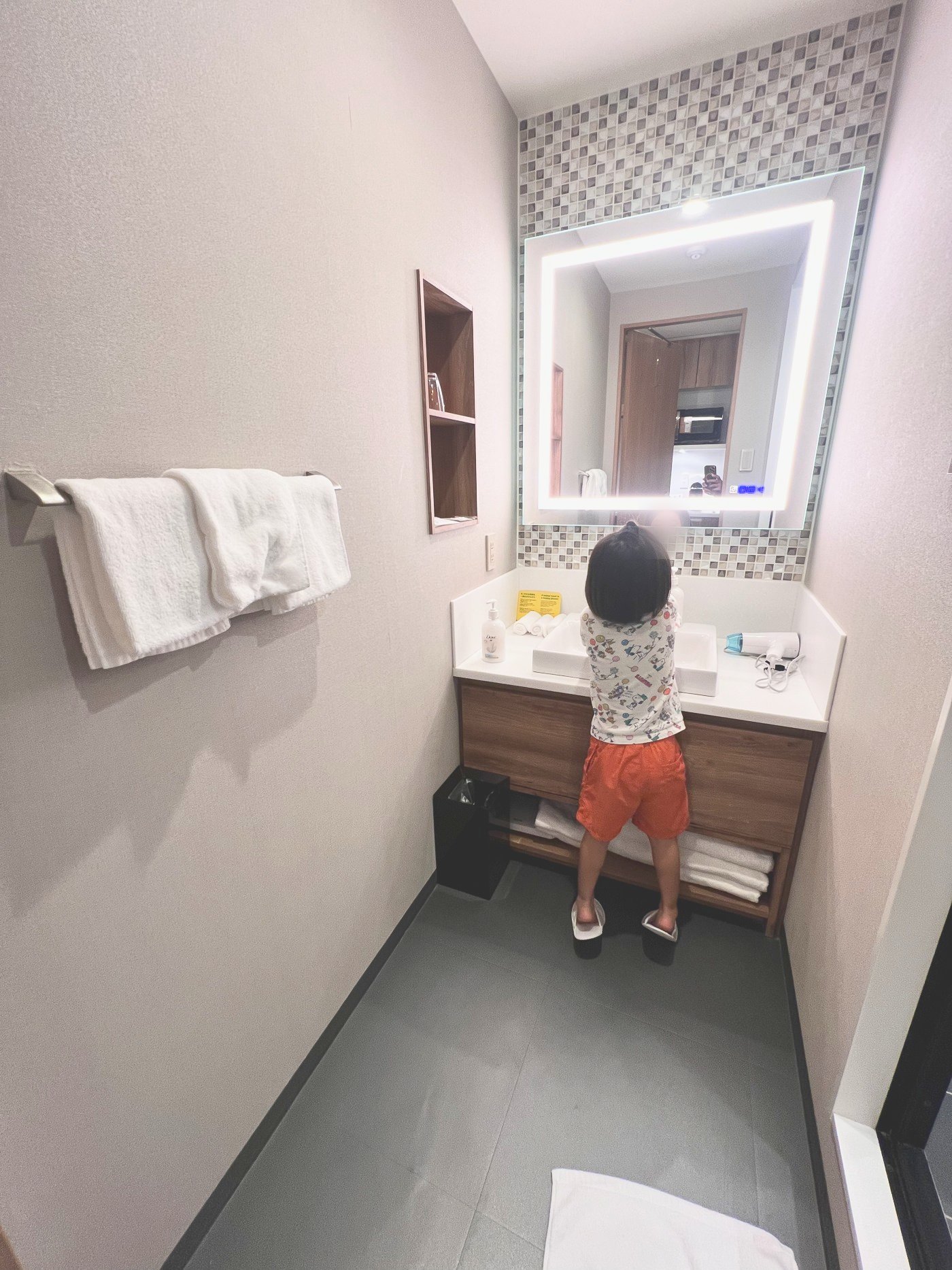 洗面台の前で背伸びして手を洗う子ども