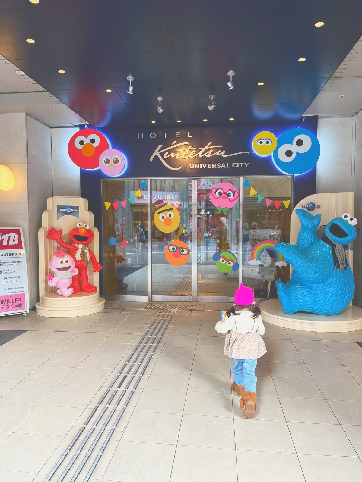 セサミストリートの装飾がされたホテルの入口へ歩く子ども