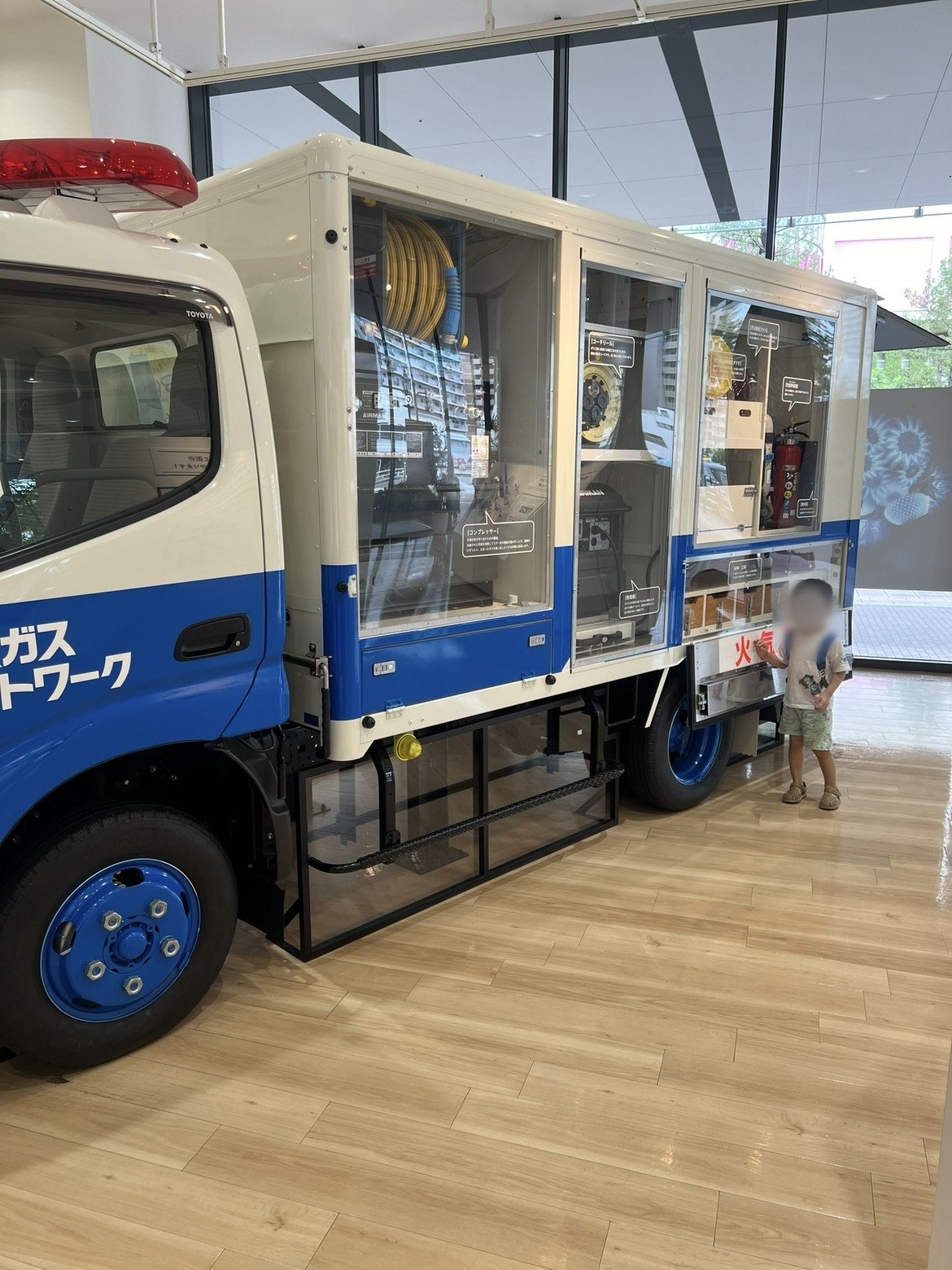 青いガス工事車両のそばに立つ子ども