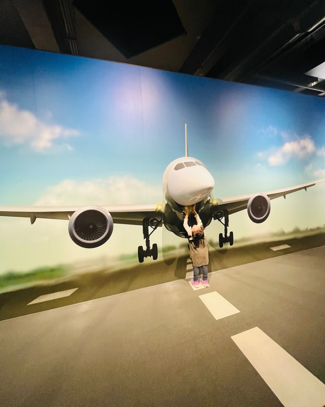 飛行機が描かれた壁に手をのばす子ども