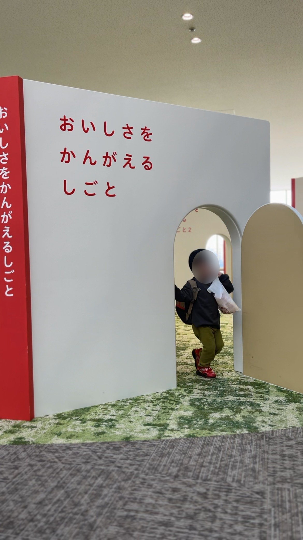 「おいしさをかんがえるしごと」と書かれたアーチをくぐる子ども