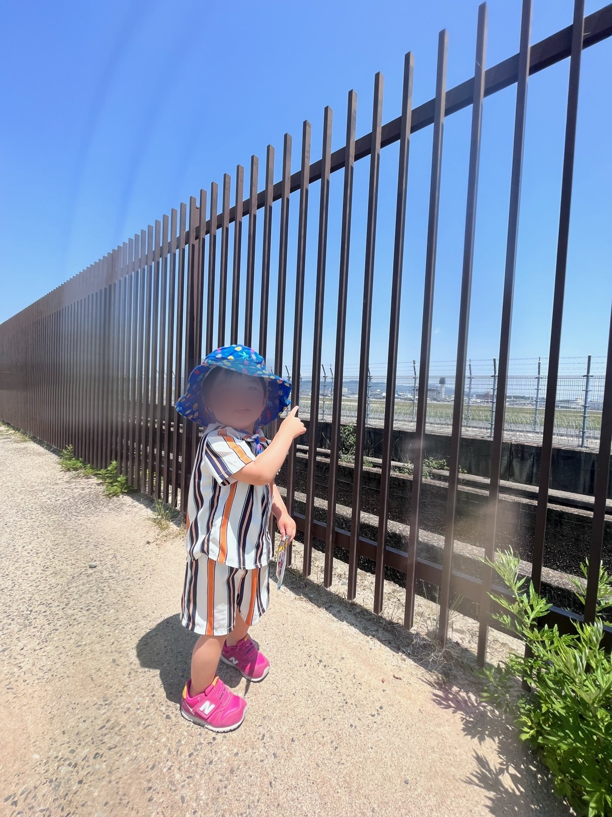 フェンス越しに滑走路を指さす子ども
