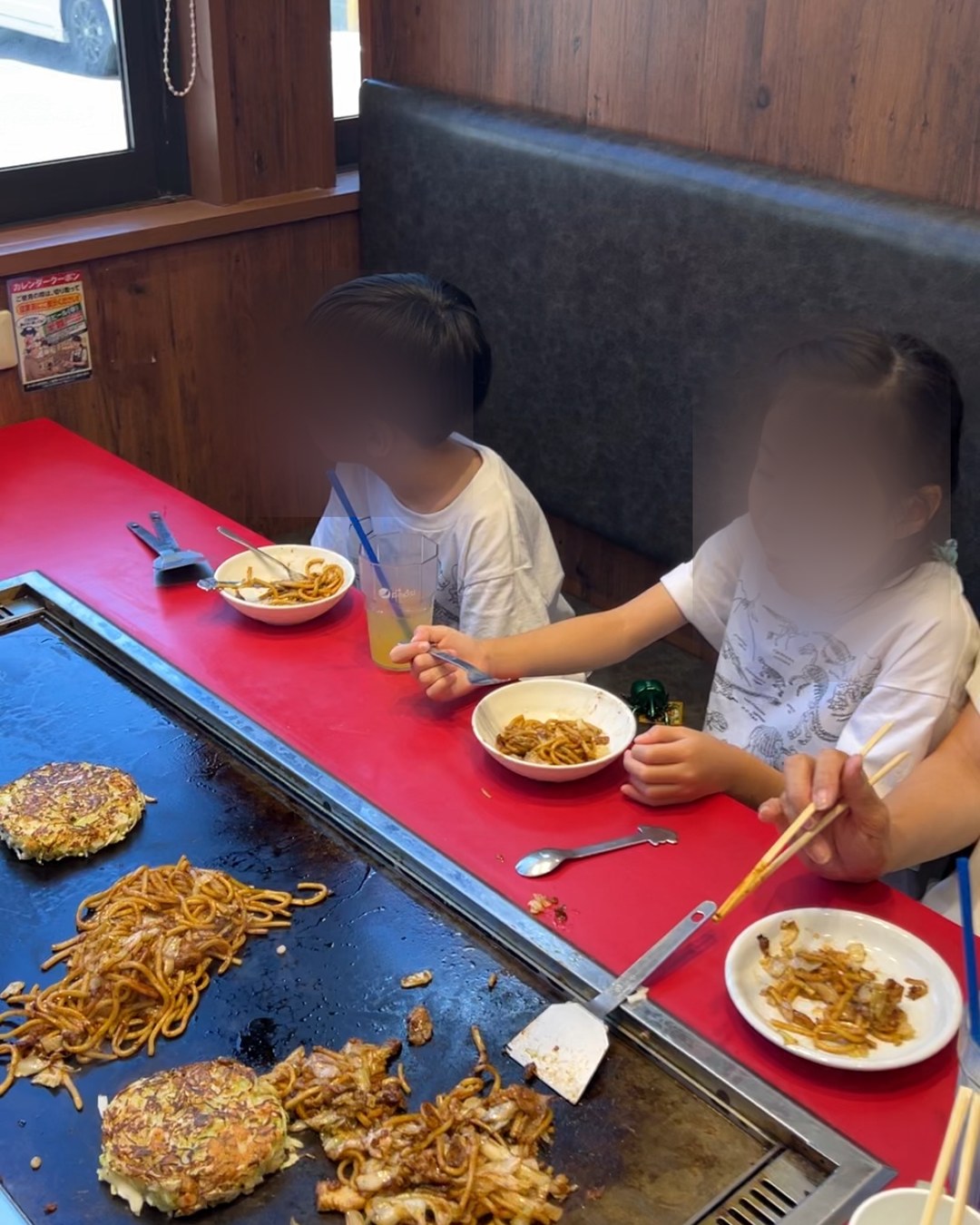 鉄板を囲むボックス席で焼きそばを食べる子どもたち