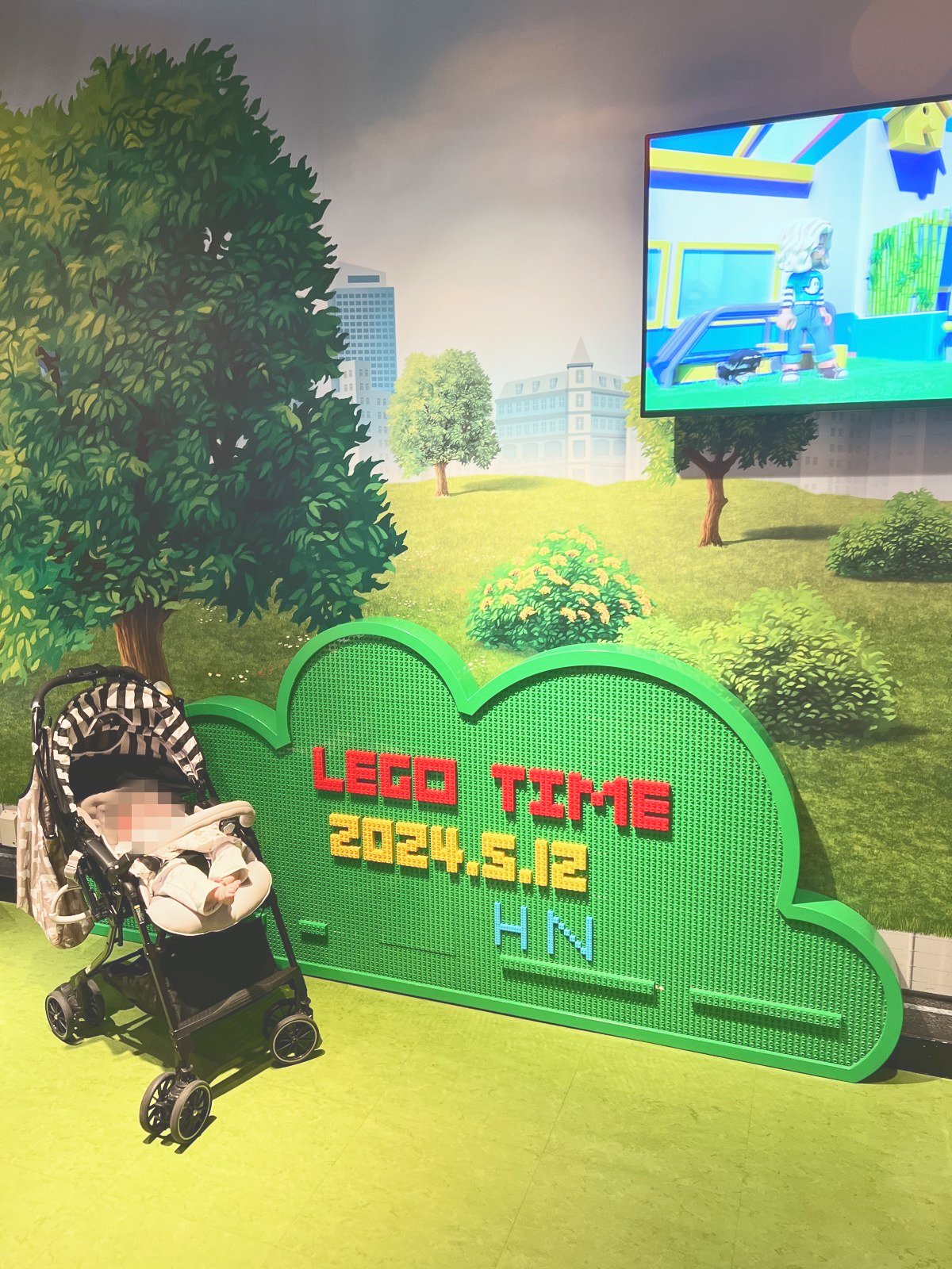 「LEGO TIME」とその日の日付が表示されたレゴのフォトスポットと、置かれたベビーカー
