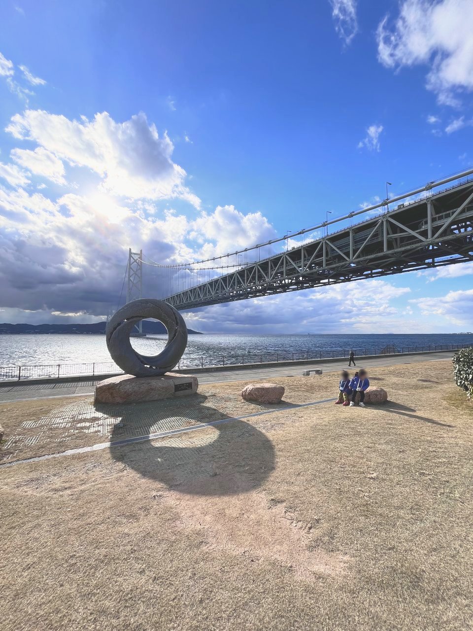 芝生の広場に置かれた輪の形のオブジェと明石海峡大橋