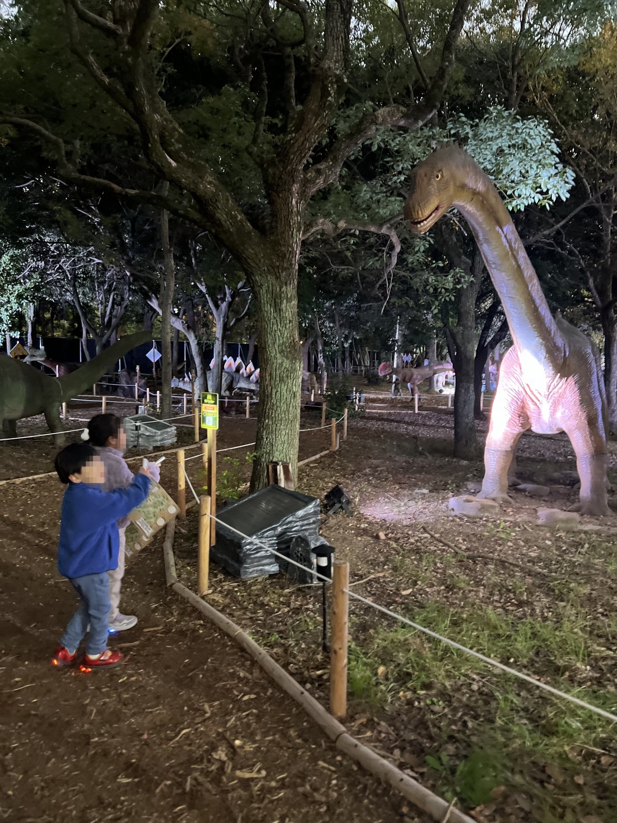 ライトアップされた首の長い恐竜を見上げる子どもたち(ナイトツアー時に撮影)