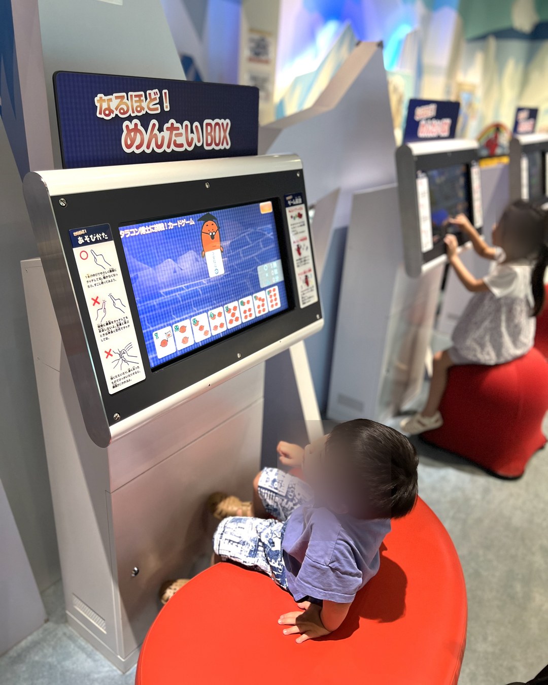 「なるほど!めんたいBOX」のタッチパネル。赤いクッションに座って遊ぶ