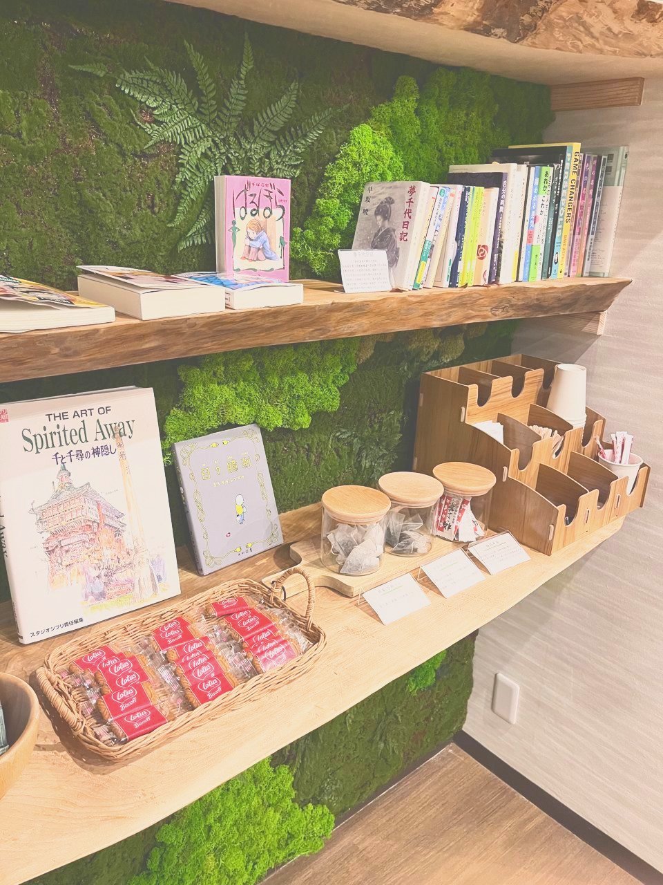 苔の壁の棚に、本やお菓子が並んでいる