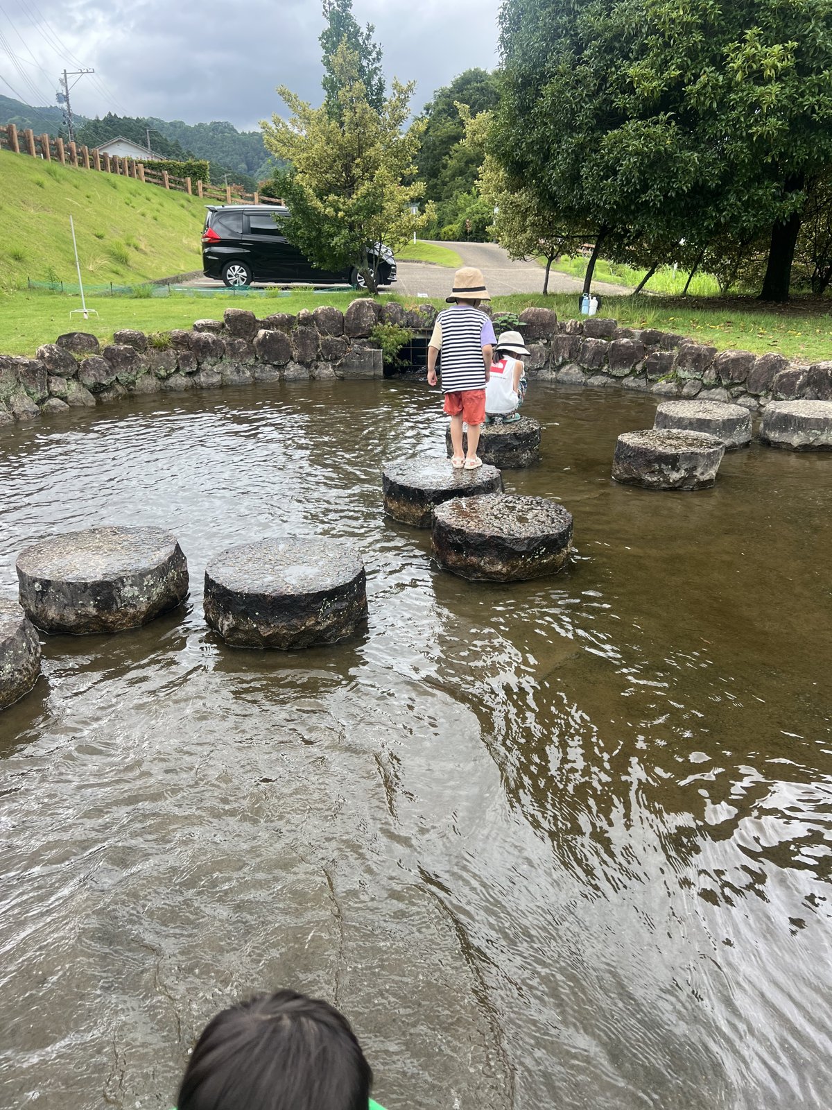 丸い飛び石がある池で遊ぶ子どもたち