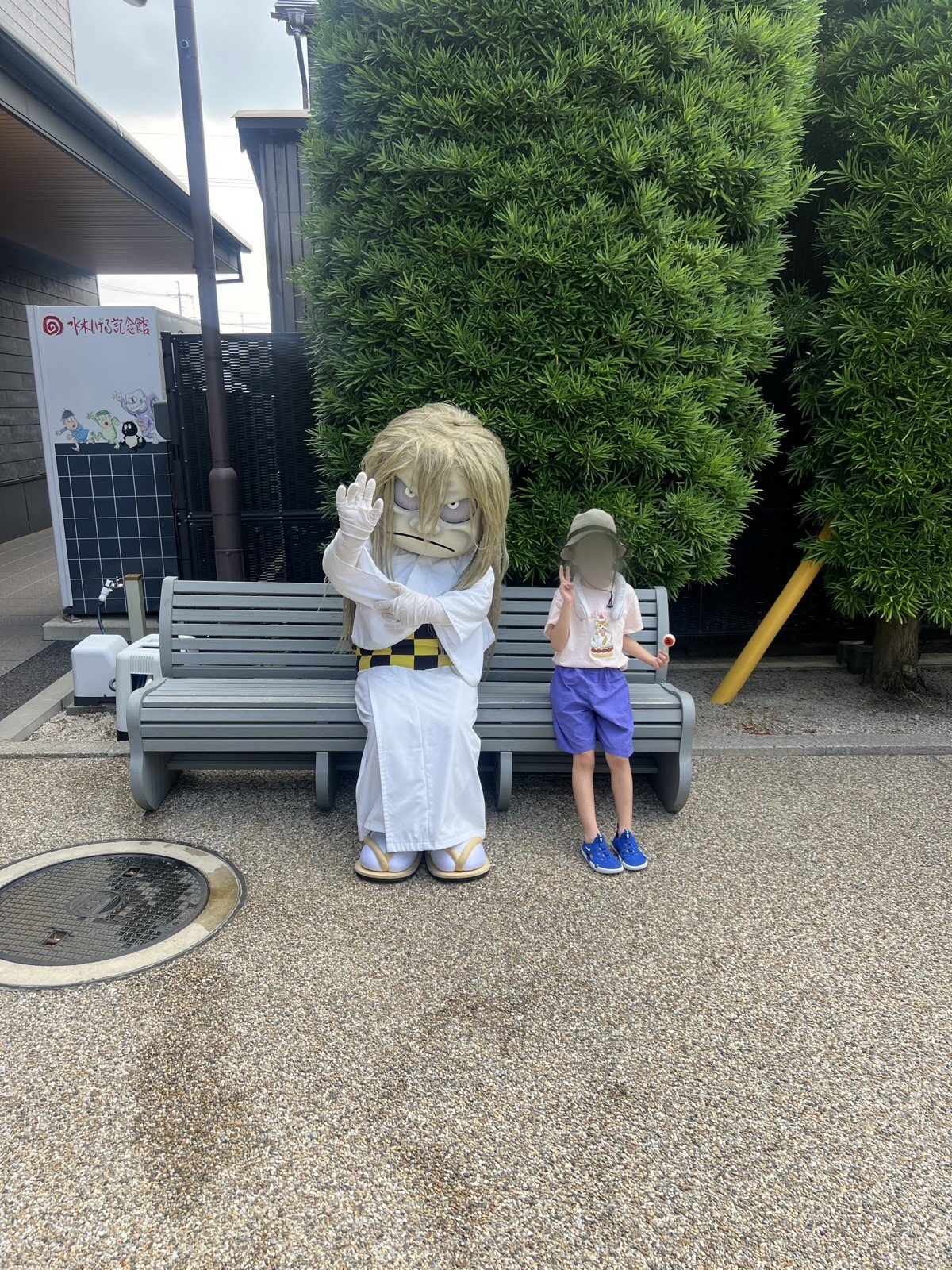 ベンチに座る妖怪の着ぐるみと、となりに座る娘