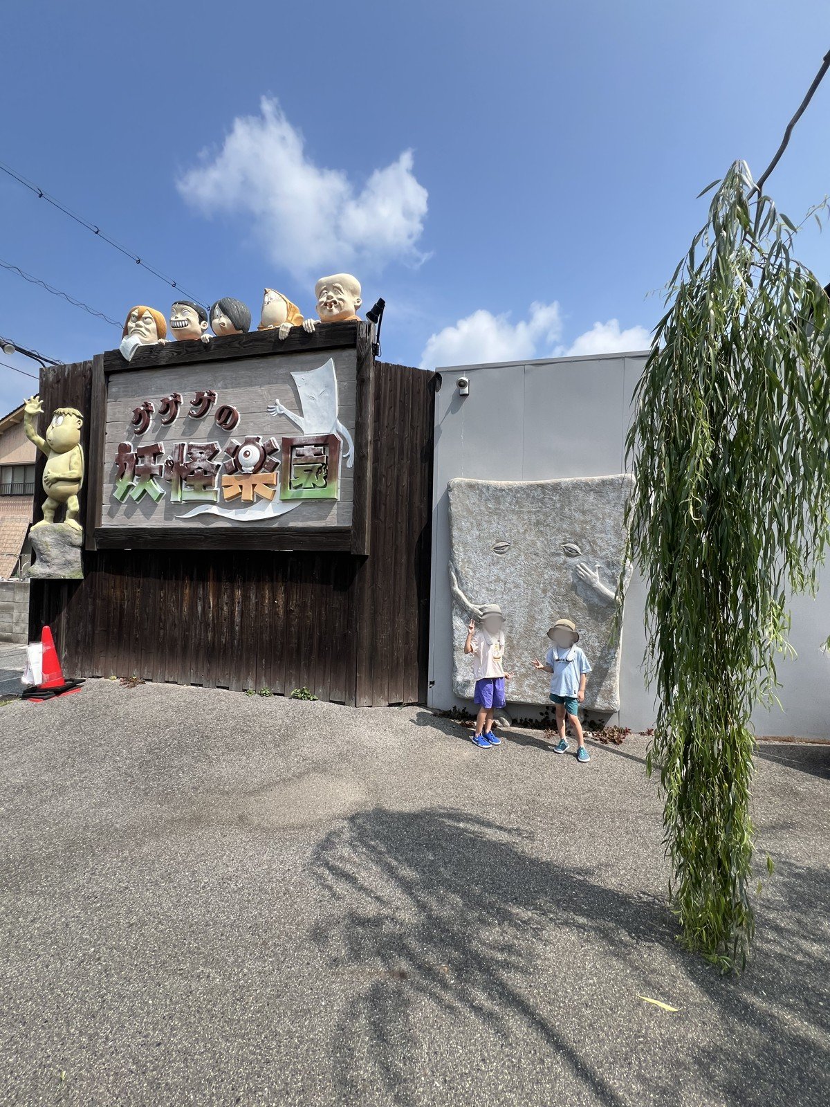 「ゲゲゲの妖怪楽園」の看板と、ぬりかべの壁の前に立つ子どもたち