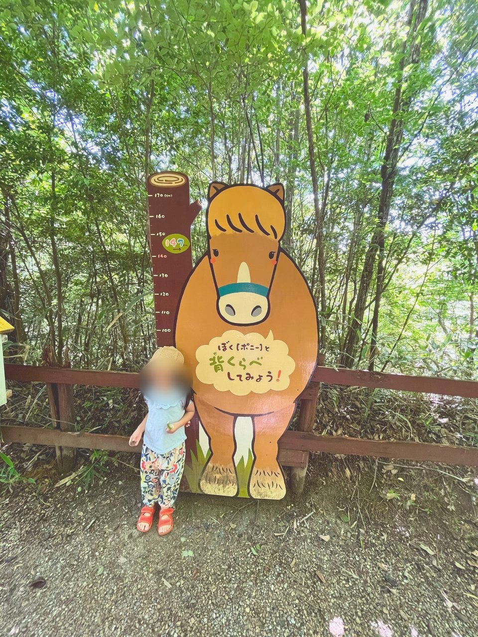 ポニーの看板と背くらべする子ども