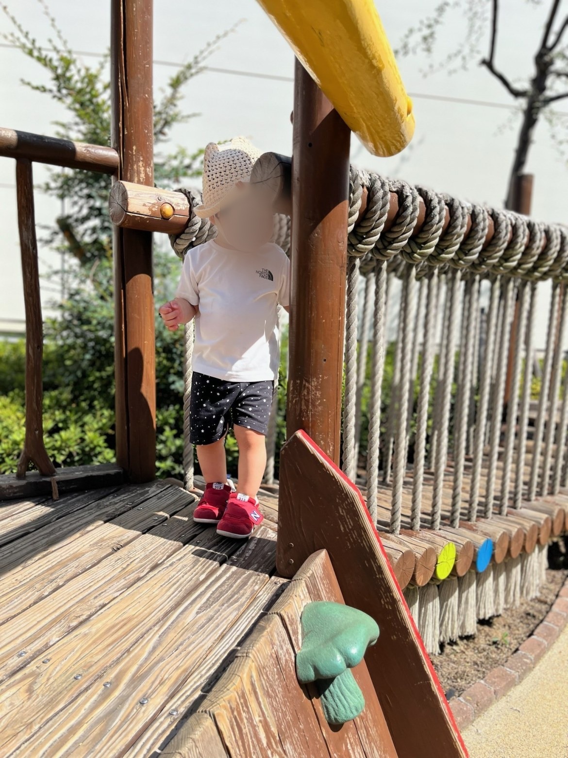 木の遊具の上を歩く1歳の子ども