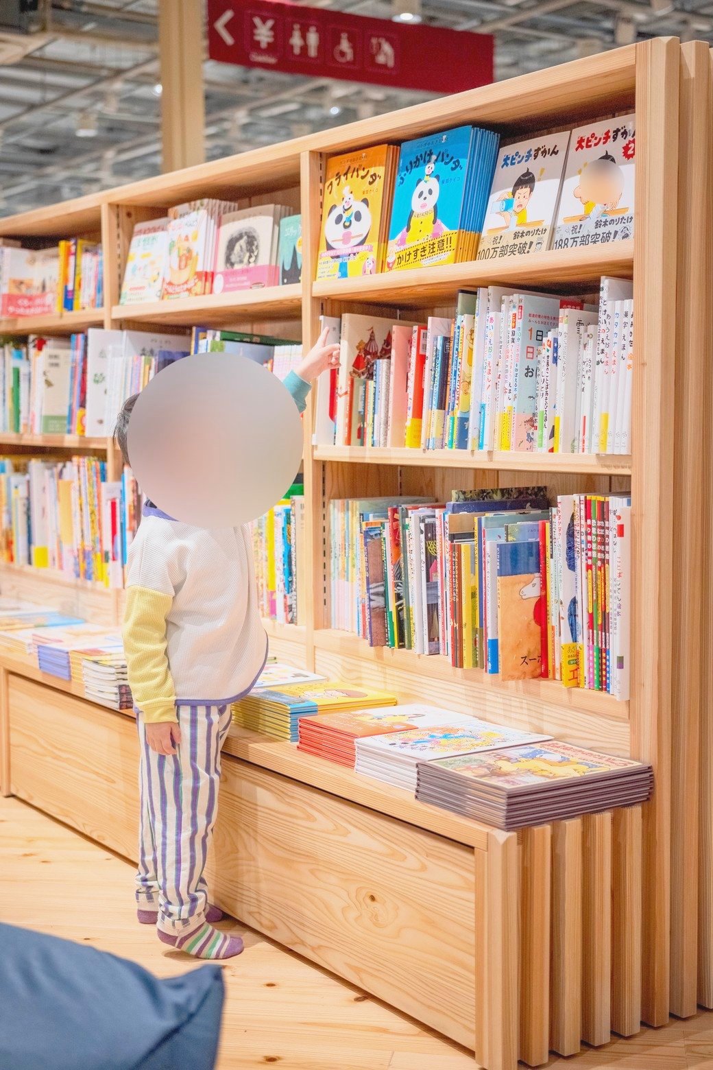 絵本の棚から1冊を選ぶ子ども
