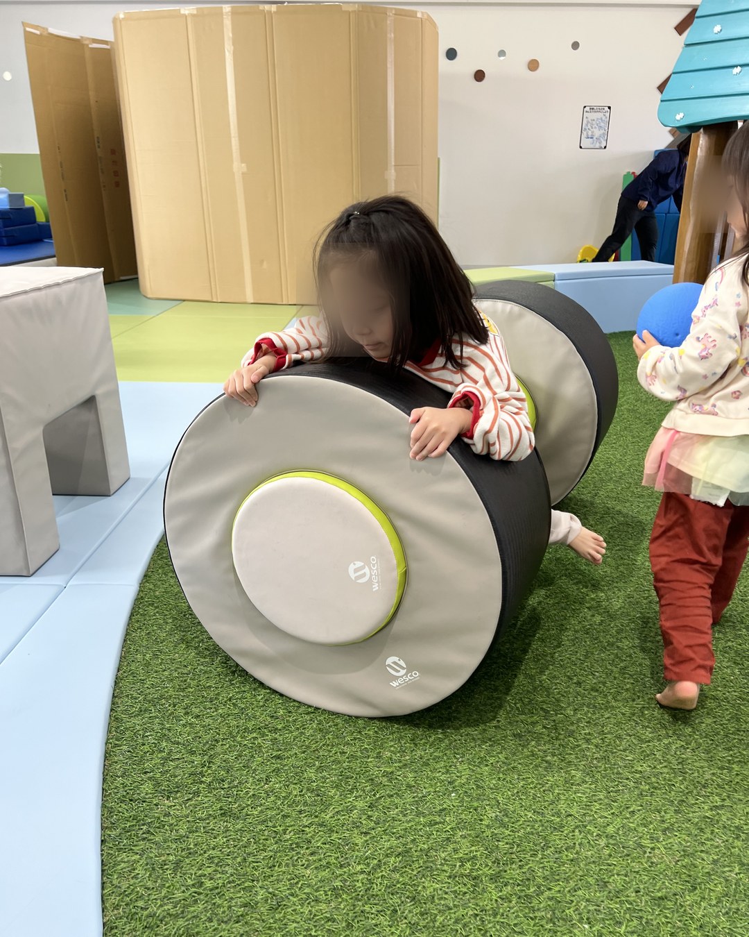 円柱形のクッション遊具を押す子ども