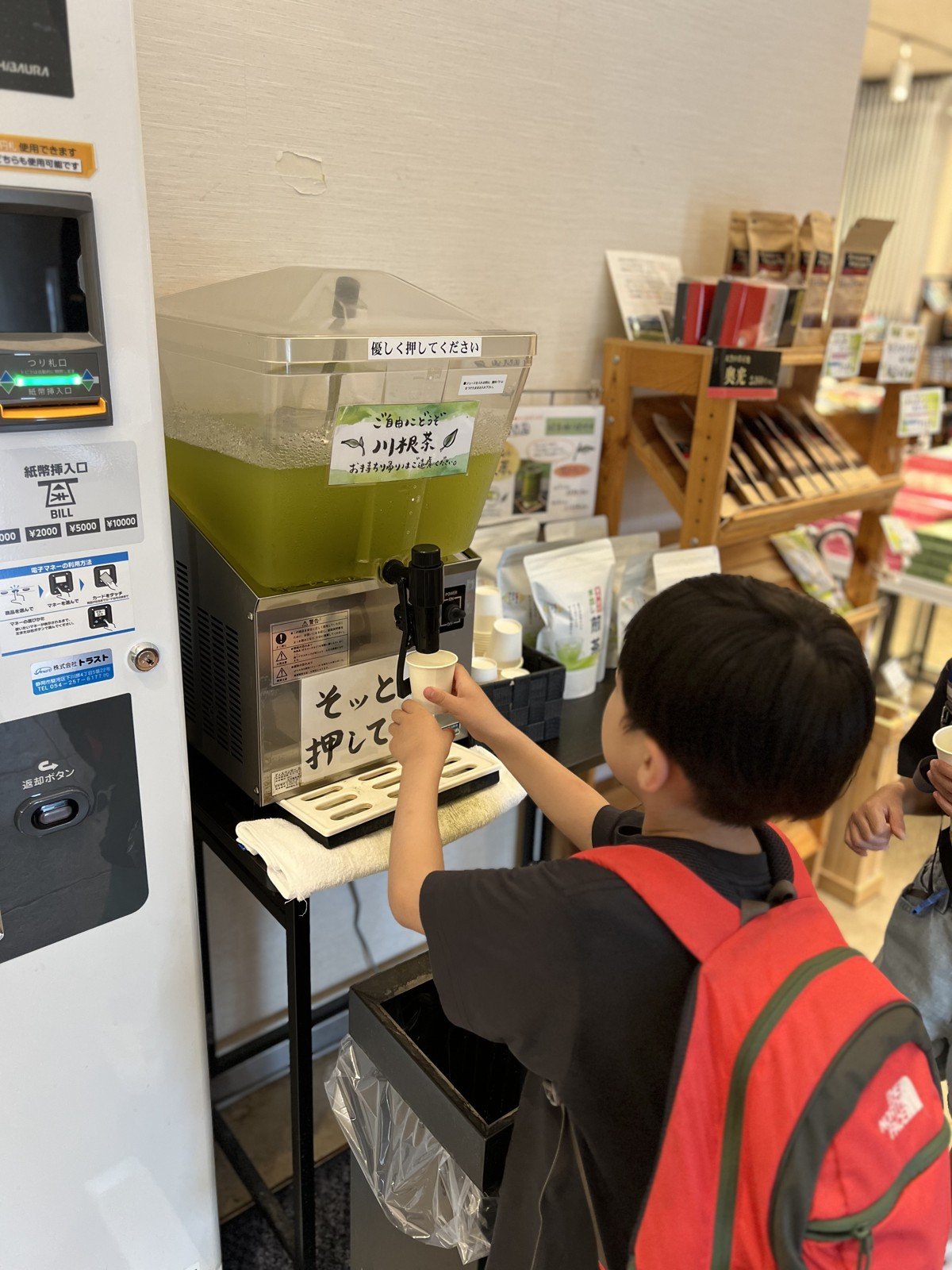 「ご自由にどうぞ 川根茶」のサーバーでお茶をつぐ息子