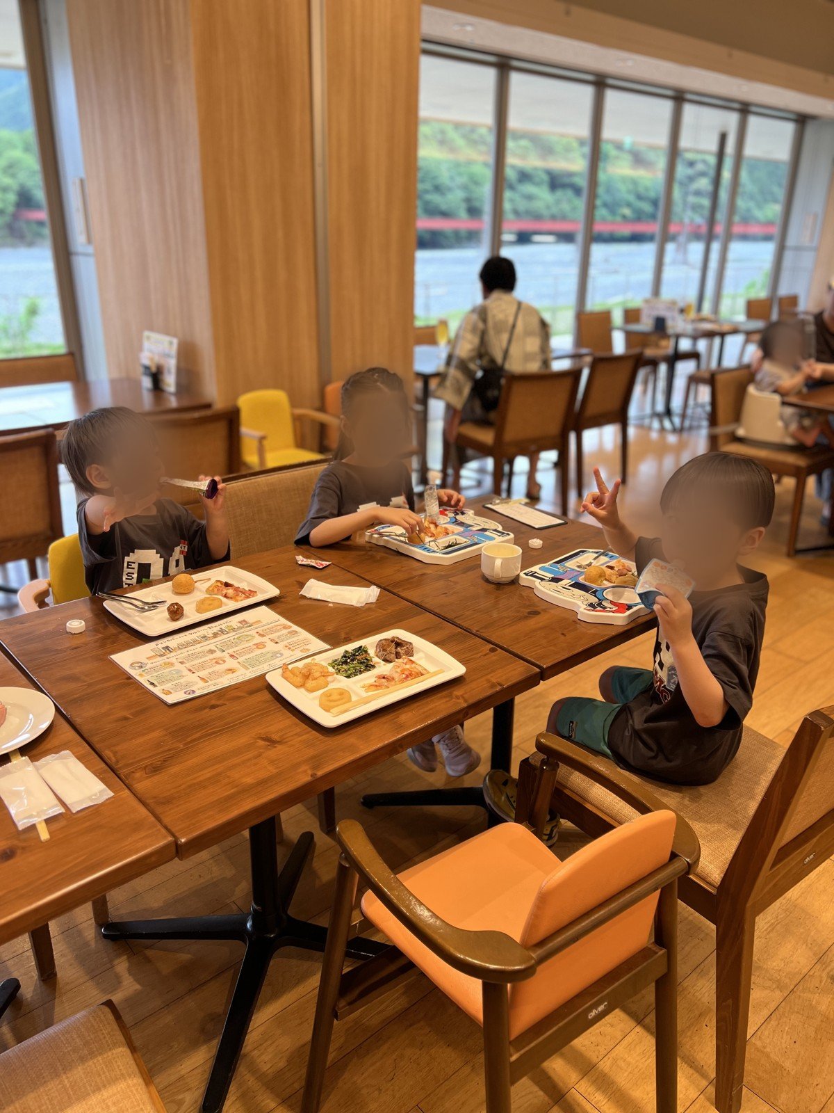 電車の形のお皿で夕食を食べる子どもたち。窓の外に赤い鉄橋