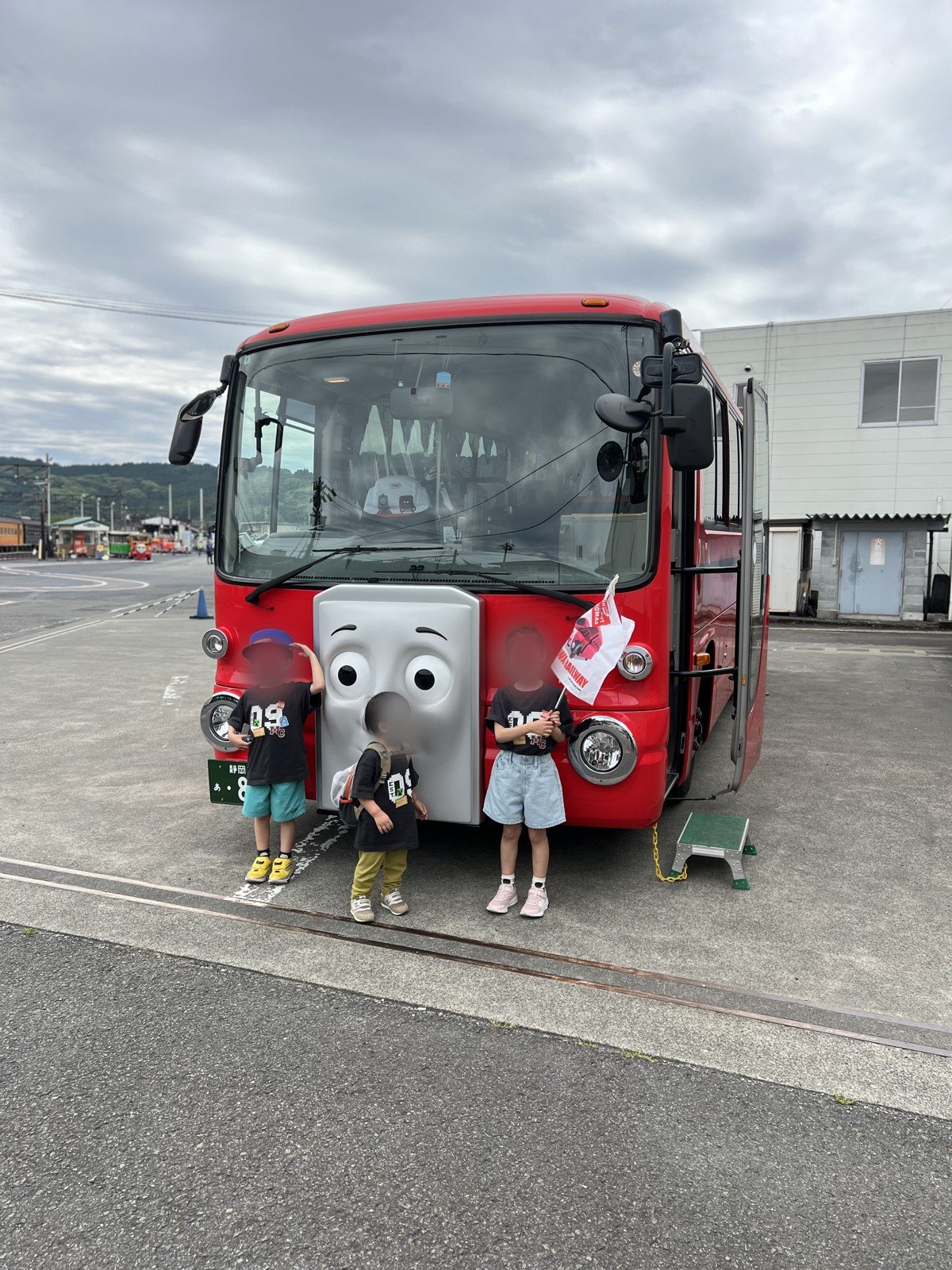 赤いバス「バーティー」の前で記念撮影する子どもたち