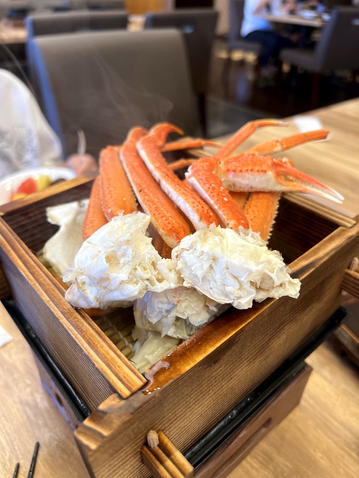 木の蒸し器に盛られた、湯気の立つカニの脚