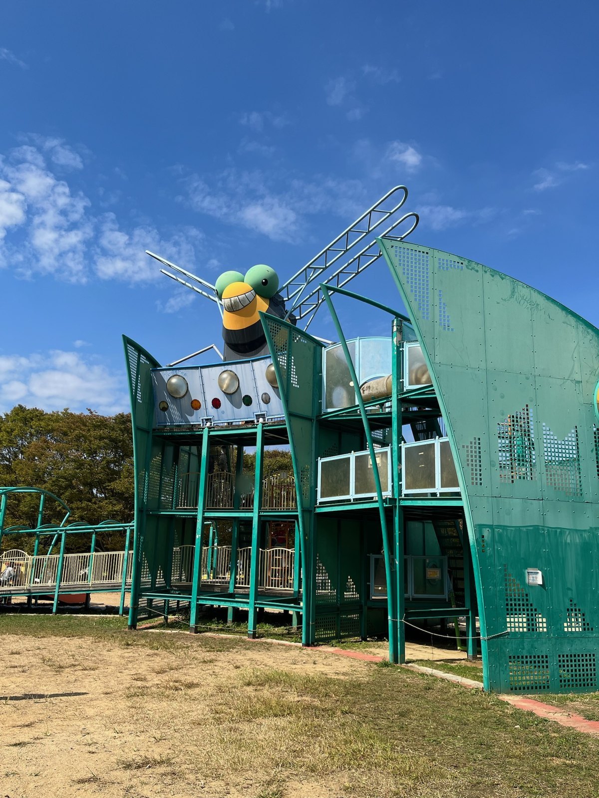 笑顔のとんぼの頭がのった、緑色の大型複合遊具