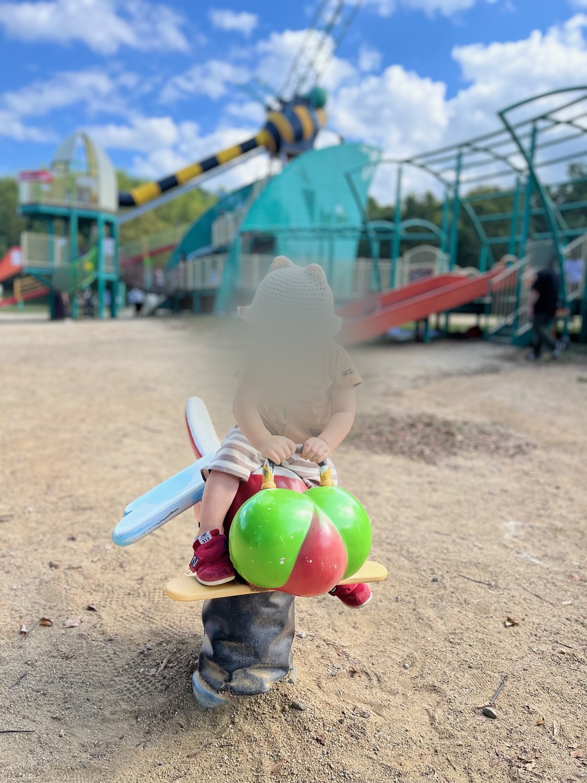 とんぼの形のスプリング遊具に乗る次男。うしろに大型遊具