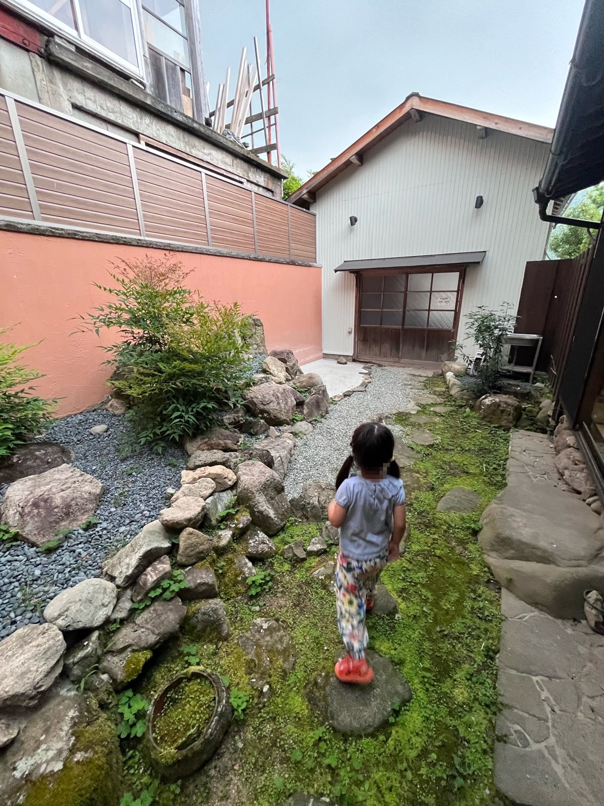 苔の生えた中庭の飛び石を歩く子ども