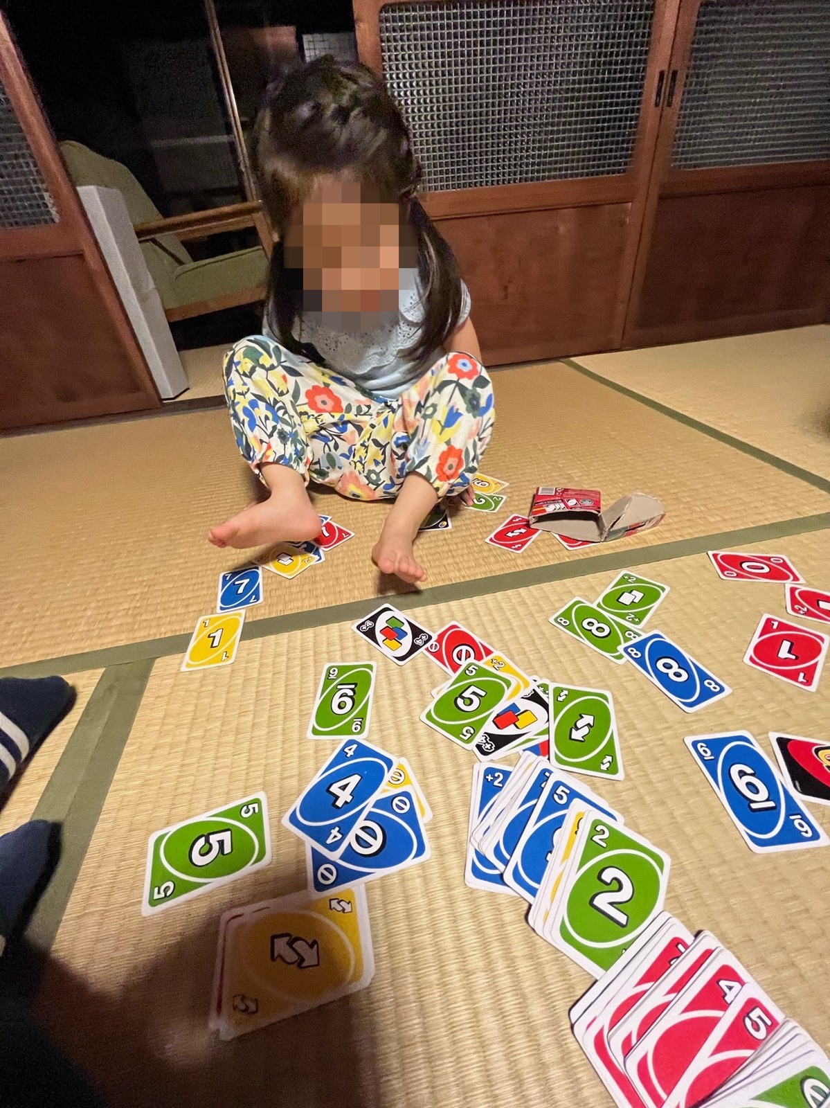 畳にUNOのカードを並べて遊ぶ子ども
