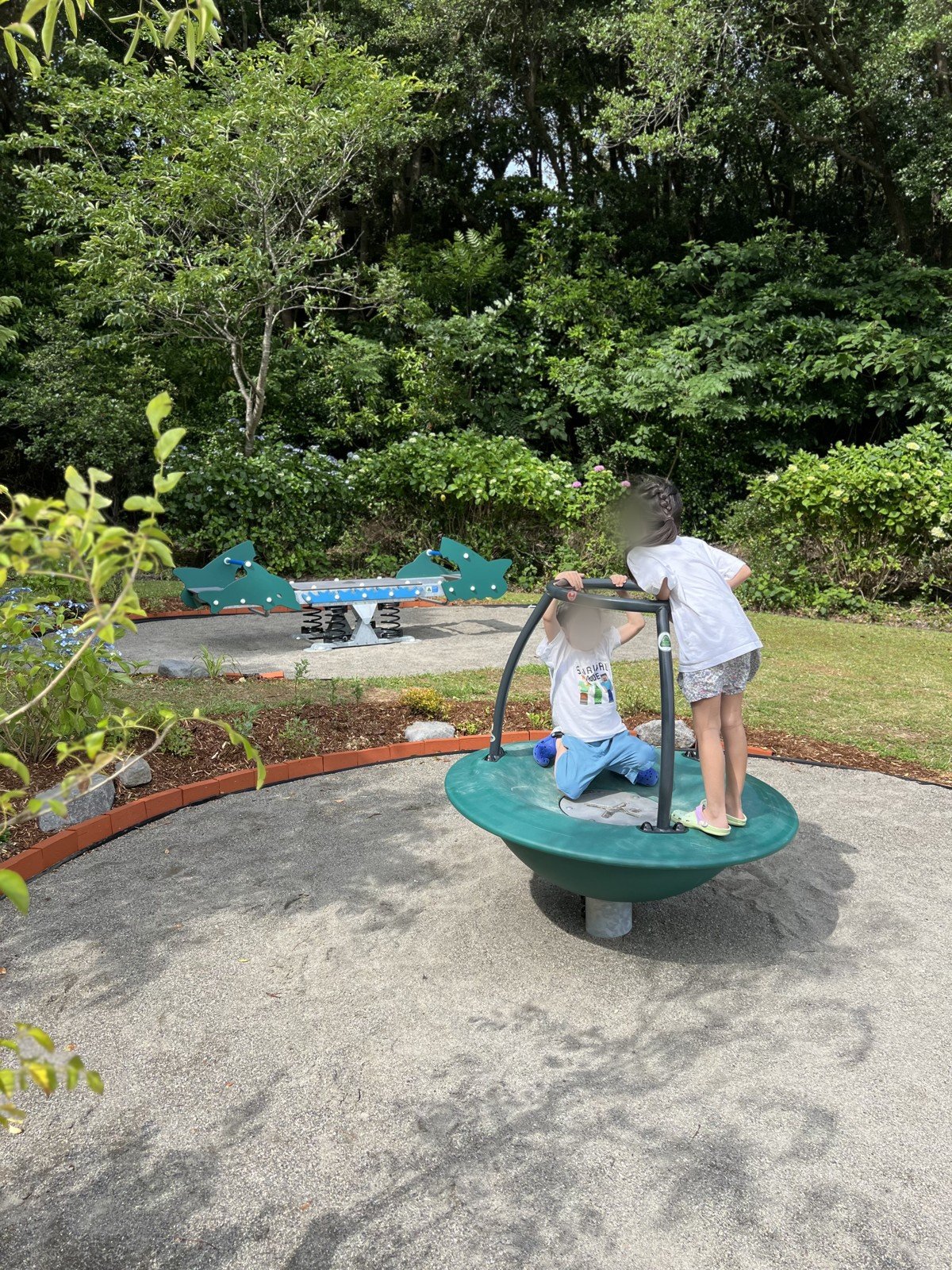 くるくる回るお皿のような遊具に乗る子どもたち
