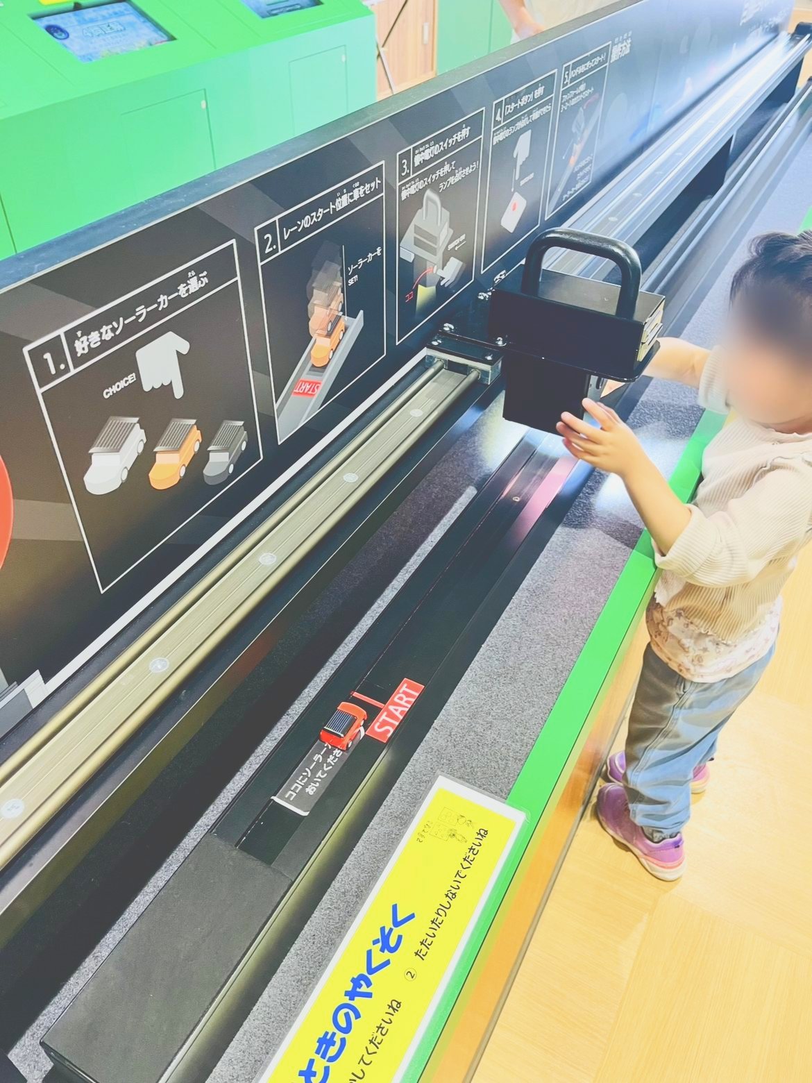 レールの上のソーラーカーを操作する子ども