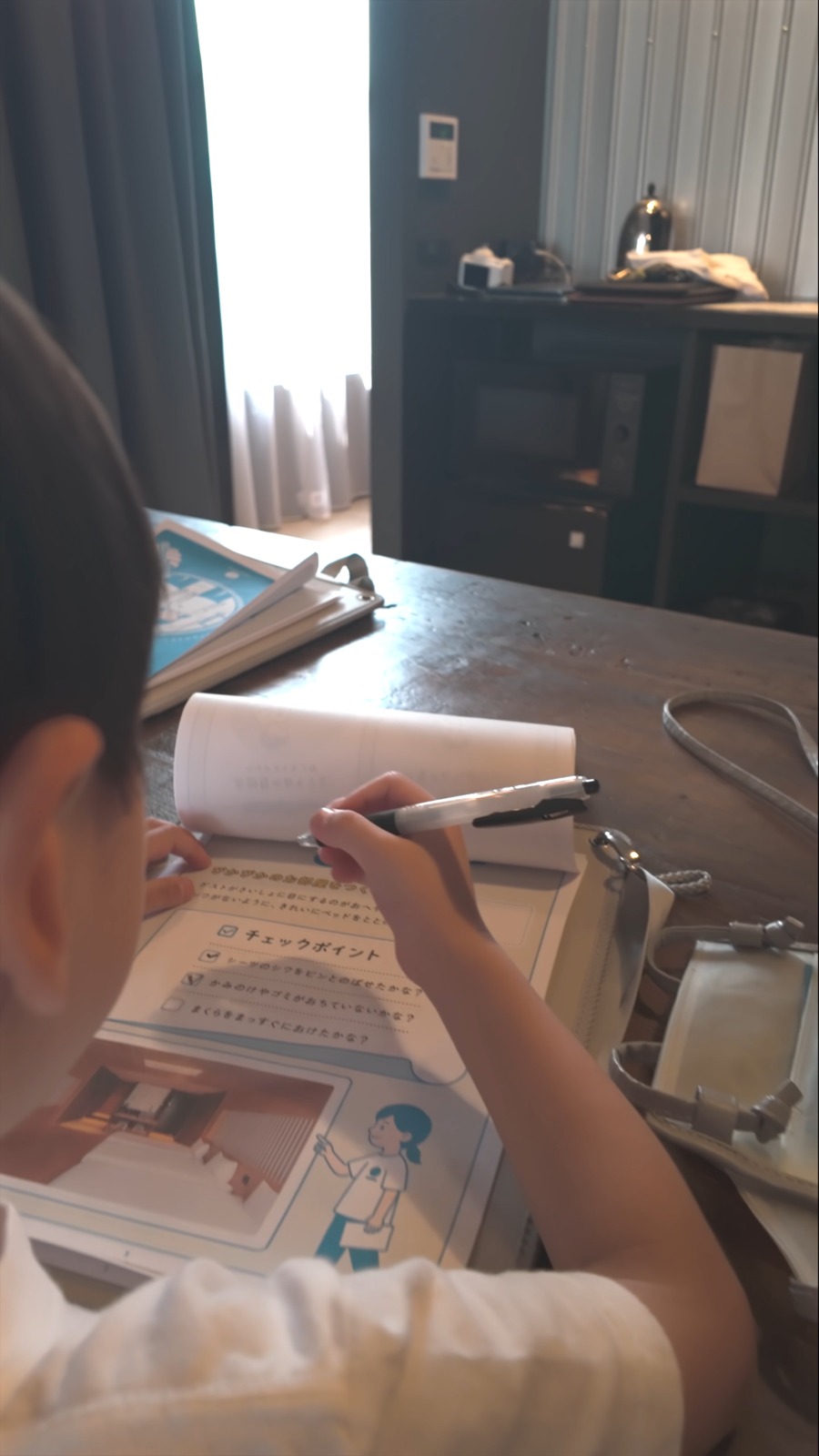 客室のテーブルで冊子に書き込む子ども