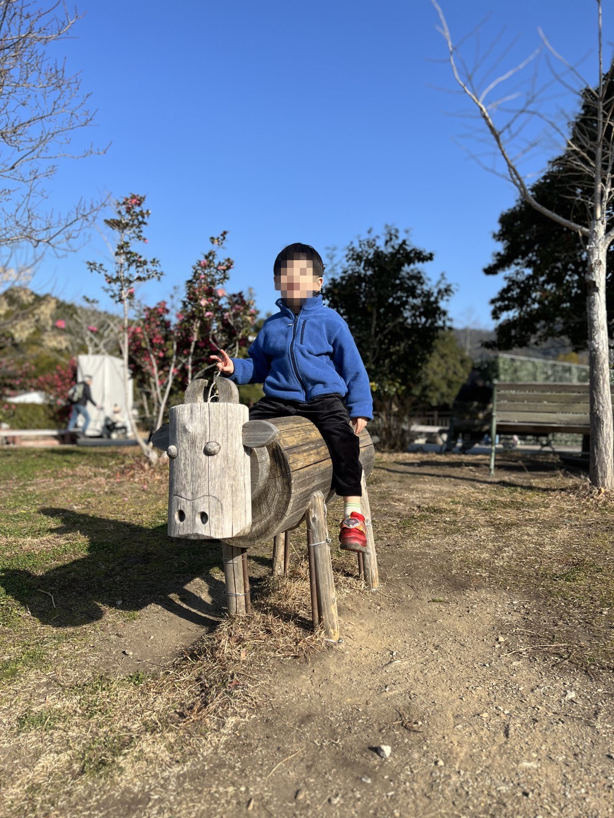 木を削って作られた動物の形の遊具にまたがる子ども