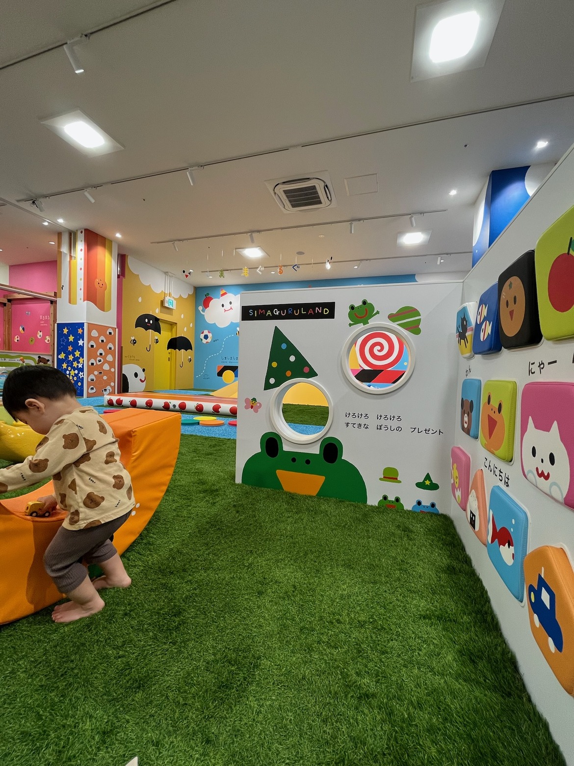 壁のキャラクターの前で遊具によじ登る子ども