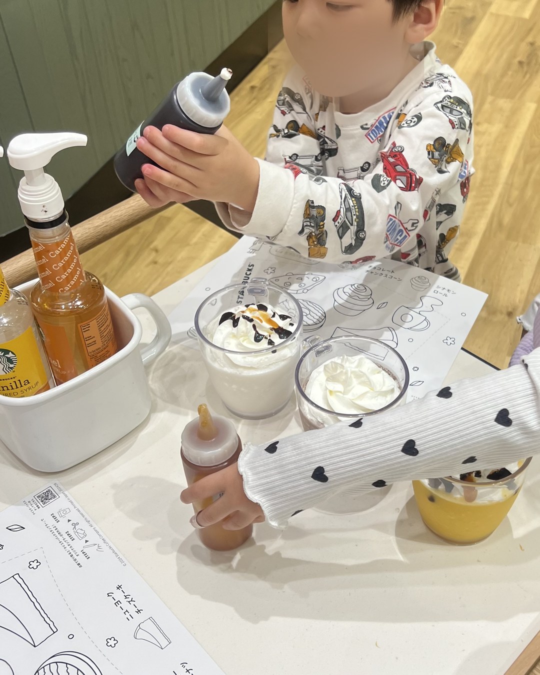 シロップのボトルを持って、自分でホイップにかける子ども