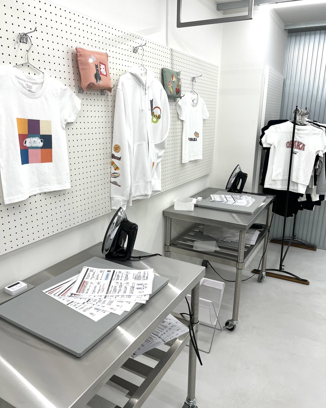ラボの作業台とアイロン、見本のTシャツやパーカー